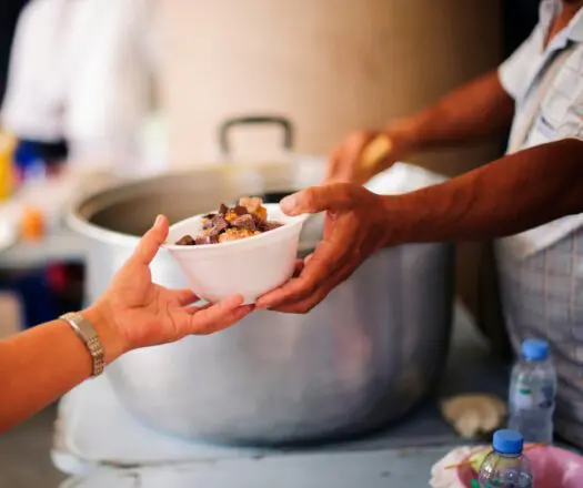 Hand reaching out to accept a bowl of food