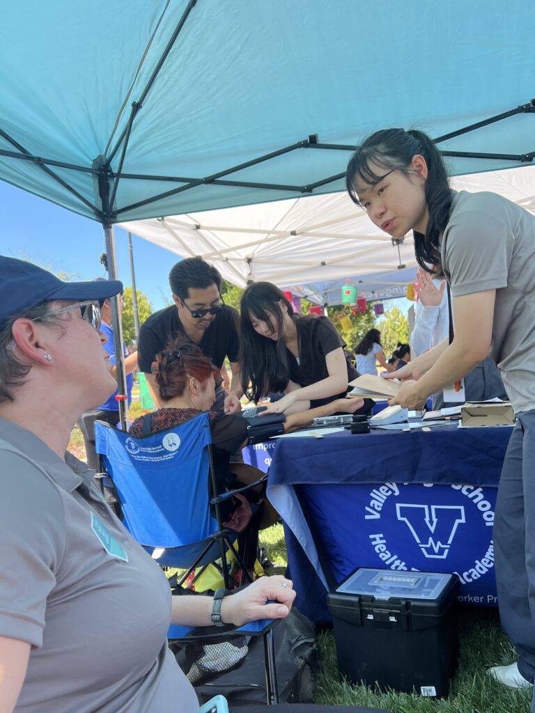 woman talking to a woman sitting down at a community health event